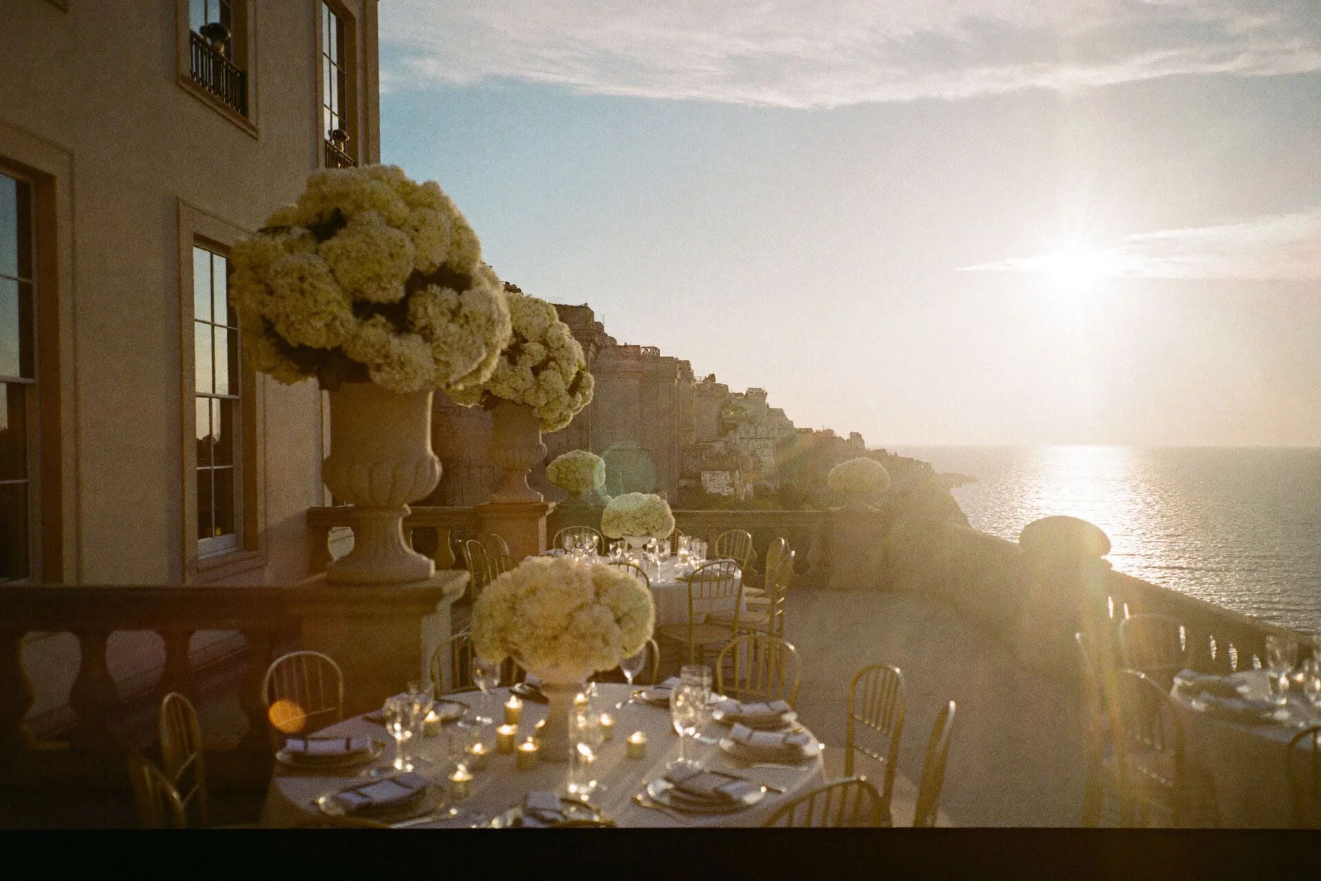 Terrazza di villa di fronte al mare al tramonto, tavoli apparecchiati